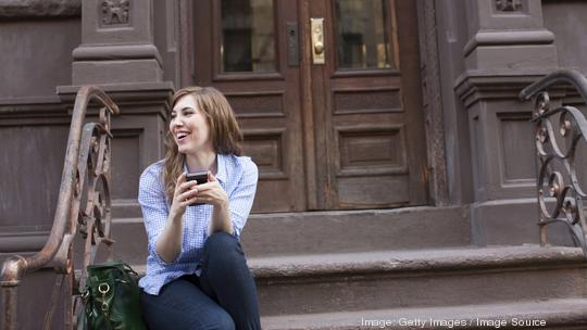 Young woman in steps of building with cellphone