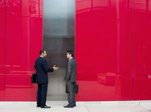 Businessmen talking near office elevator