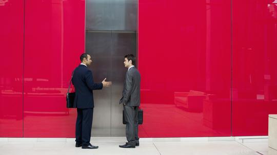 Businessmen talking near office elevator