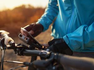 An unrecognizable mountain biker attaching his phone to a bike mount