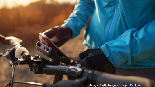 An unrecognizable mountain biker attaching his phone to a bike mount