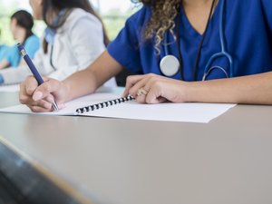 Unrecognizable medical student writes in class workbook