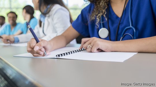 Unrecognizable medical student writes in class workbook