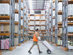 Worker pushing hand truck in warehouse