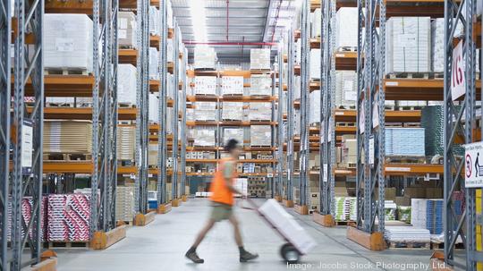 Worker pushing hand truck in warehouse