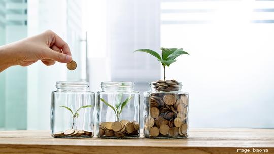 Woman putting coin in the jar with plant