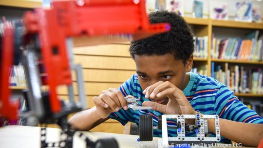 Boy assembling plastic blocks in library