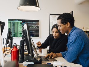 engineers coding over laptop on desk in office