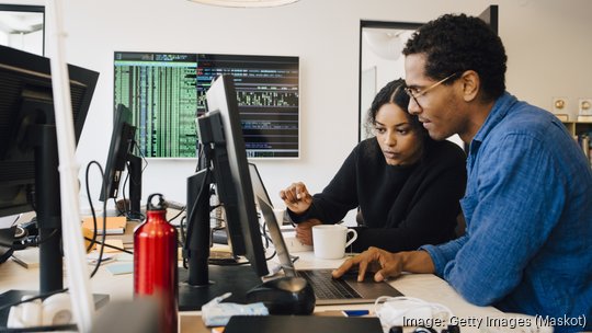 engineers coding over laptop on desk in office