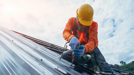 Roofer worker in special protective work wear and gloves.