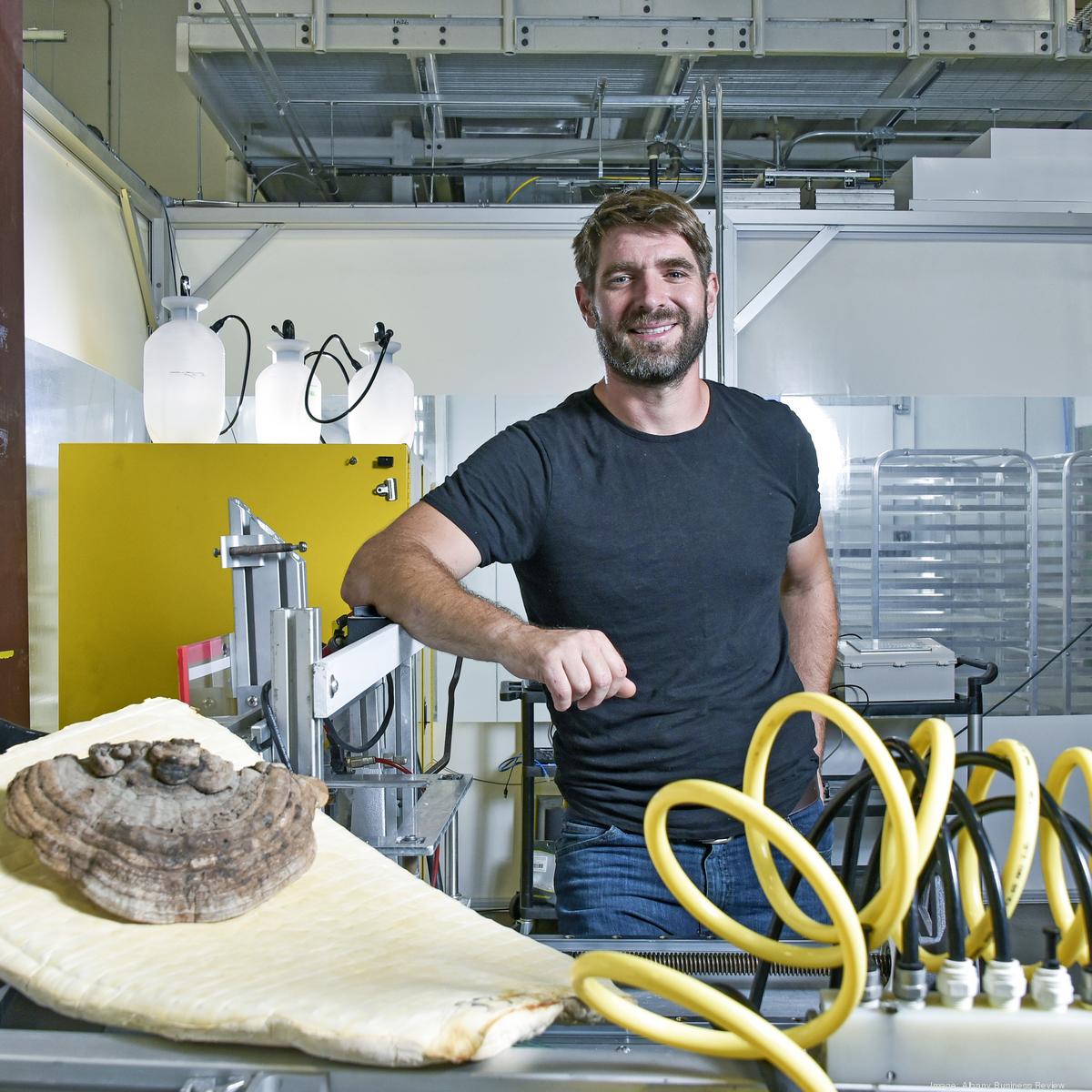 Eben Bayer, CEO of Ecovative, smiling confidently in a navy blazer and light blue shirt against a white background.