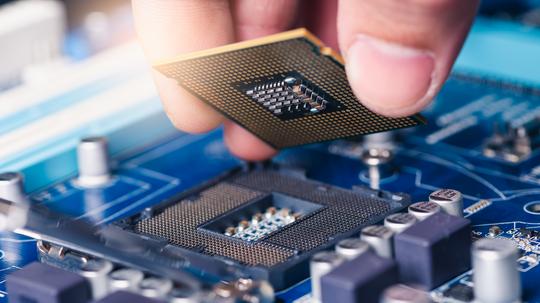 the technician laying the CPU chip in the motherboard's socket