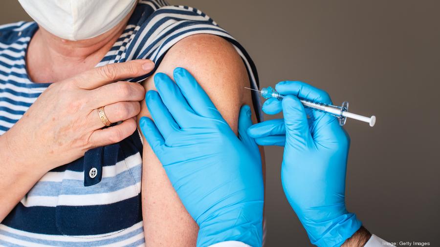 Close up of older woman getting injected with a vaccine in upper arm.