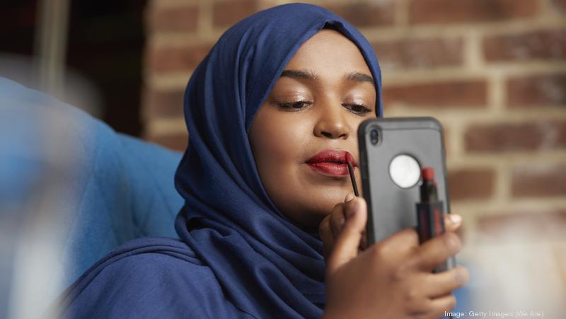 Woman applying lipstick using smartphone as a mirror