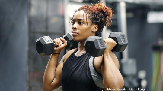 Fit, young woman working out with hand weights in a fitness gym.