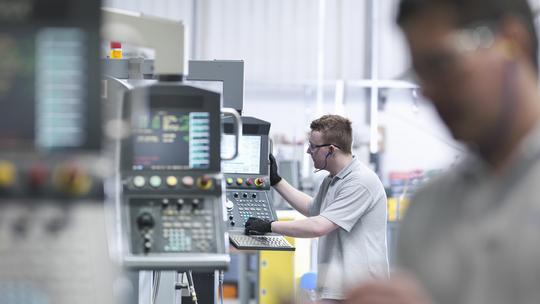 Engineers operating CNC lathes in factory