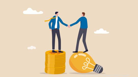 Idea pitching, fund raising and venture capital, selling business or merger agreement concept, entrepreneur businessman standing on lightbulb idea lamp shaking hands with VC on money coins stack.