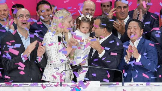 SoundHound founder and CEO Keyvan Mohajer standing at Nasdaq podium with a crowd of people next to his wife and baby daughter