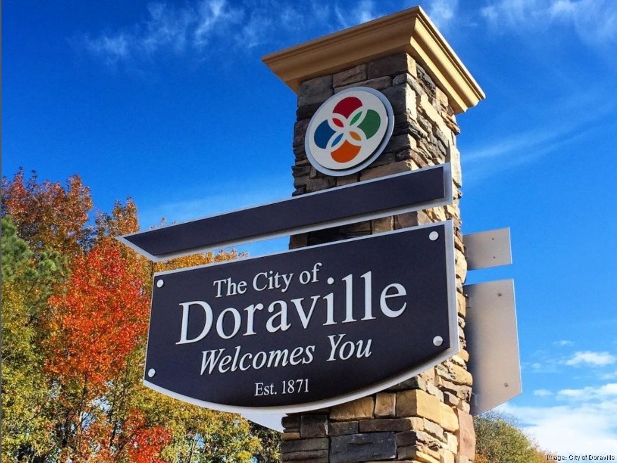 Doraville gateway sign with multicolor emblem, stone pillar and serif welcome lettering