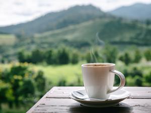 Close-Up of Coffee Cup on Table Against Landscape Scenery Mountain Hill  Background.