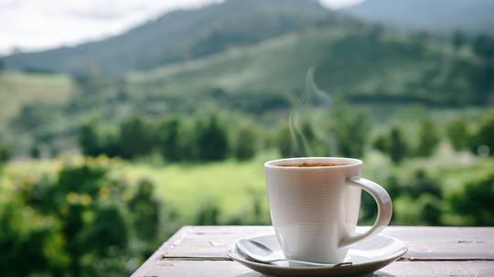 Close-Up of Coffee Cup on Table Against Landscape Scenery Mountain Hill  Background.