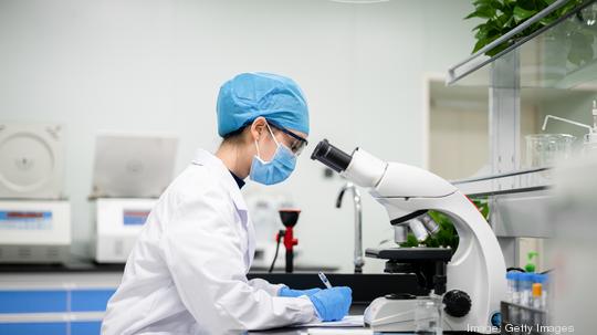 A young woman doctor was working at a microscope