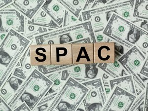 SPAC, special purpose acquisition company symbol. Wooden cubes with word 'SPAC' on beautiful background from dollar bills, copy space. Business and SPAC, special purpose acquisition company concept.