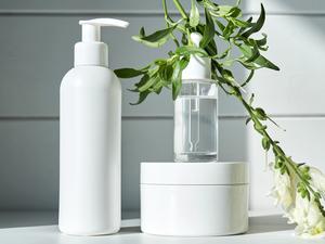 Skin care products on a chest of drawers against a white wooden wall. - stock