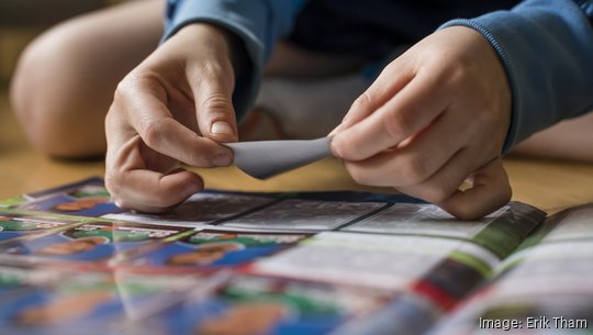 8 year old boy pasting soccer trading cards into his scrapbook