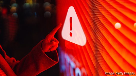 Close-up of  female hand touching illuminated digital screen displaying a warning sign