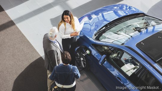 High angle view of saleswoman showing car to customers at showroom