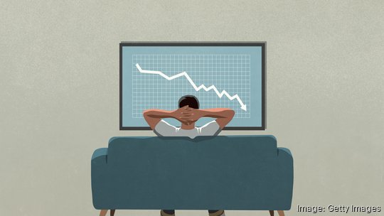 Man on sofa watching stock market decline on TV