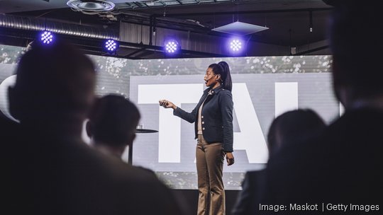 Female public speaker with remote controller giving speech at tech event