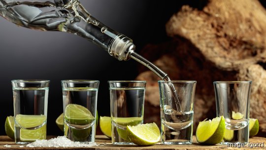 Silver Tequila with salt and lime slices on an old wooden board.