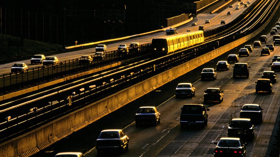 Metro rail train traveling on median between traffic on I-66, Fairfax, VA in low-angled morning or evening sunlight.