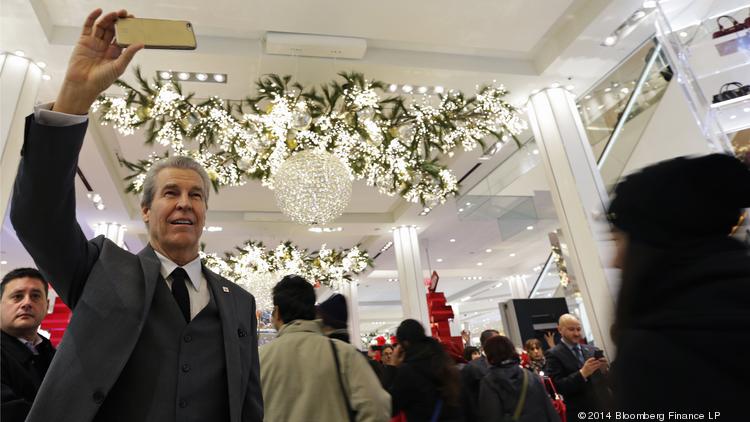 Terry Lundgren, chairman and chief executive officer of Macy's Inc., second left, takes a video clip with a smartphone at the company's store ahead of Black Friday 2014 in New York.