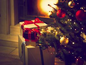 Toned photo of Christmas tree and gift boxes against burning fireplace