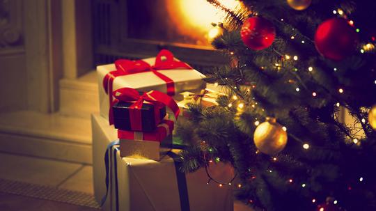 Toned photo of Christmas tree and gift boxes against burning fireplace